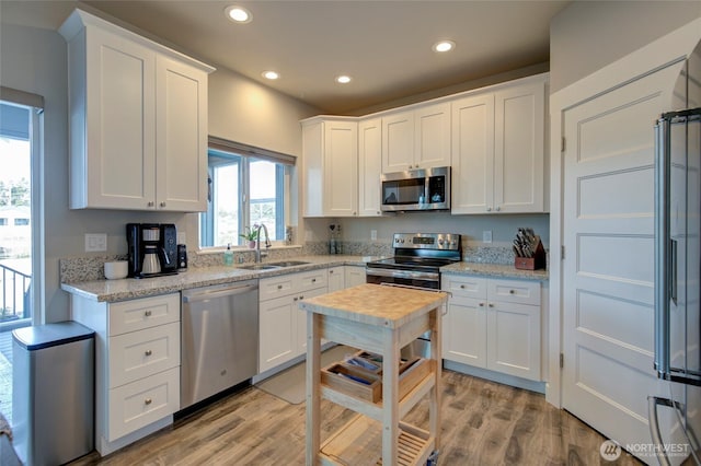 kitchen featuring stainless steel appliances, light wood-style floors, white cabinetry, a sink, and recessed lighting