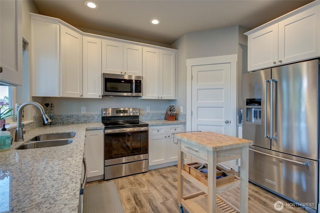 kitchen featuring stainless steel appliances, light wood-type flooring, white cabinetry, and a sink