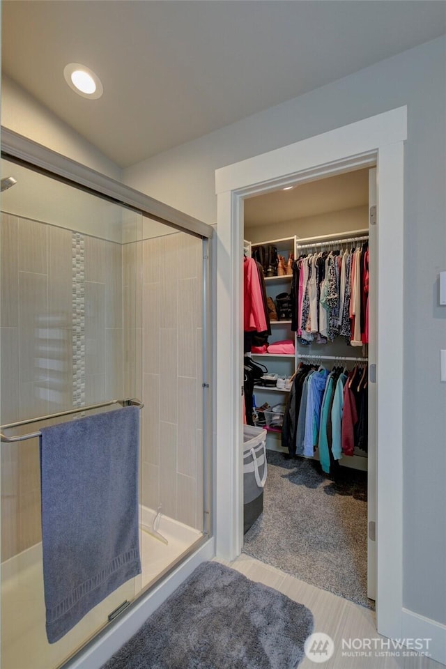 full bath featuring a stall shower, a walk in closet, and recessed lighting