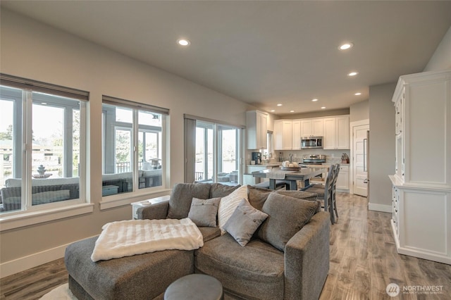 living area featuring light wood-style floors, baseboards, and recessed lighting