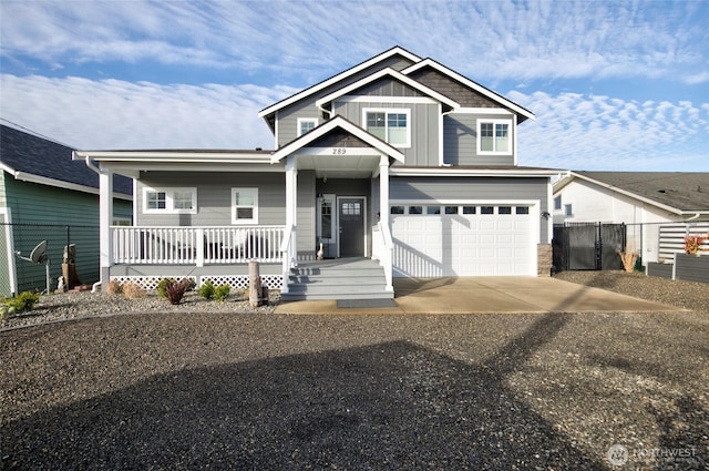 view of front of home with an attached garage, covered porch, fence, driveway, and board and batten siding