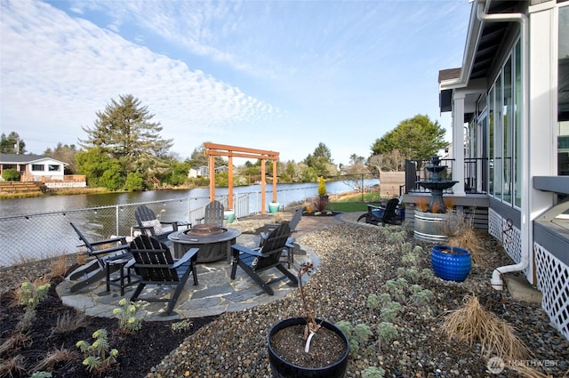 view of yard featuring a fire pit, a patio area, a water view, and fence