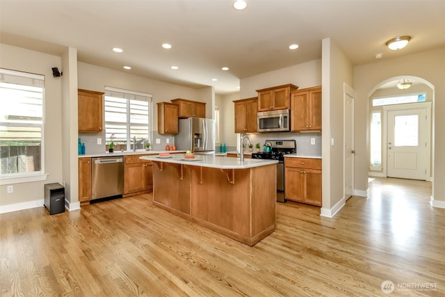 kitchen featuring light wood-style flooring, appliances with stainless steel finishes, brown cabinetry, and light countertops