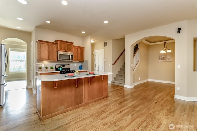 kitchen with visible vents, brown cabinetry, stainless steel appliances, light countertops, and light wood-type flooring