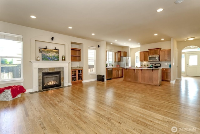 unfurnished living room with light wood-style floors, recessed lighting, baseboards, and a tile fireplace