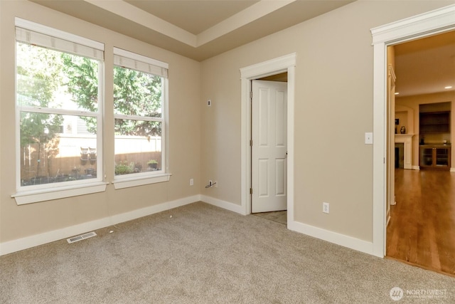 carpeted spare room with a fireplace, visible vents, and baseboards