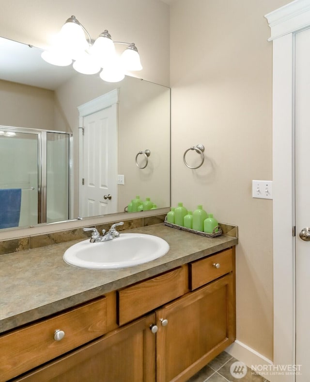 bathroom with baseboards, vanity, a shower stall, and tile patterned floors