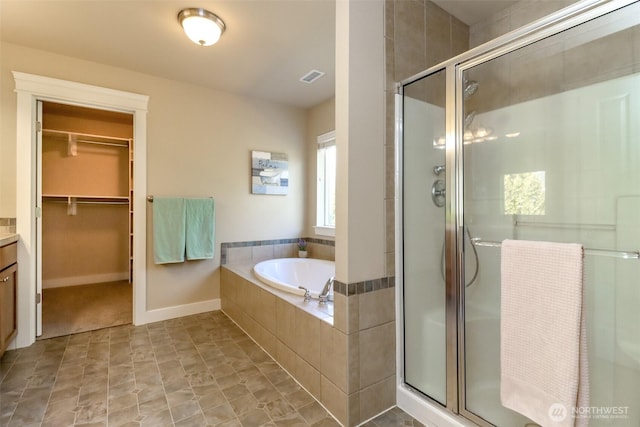 full bathroom featuring a stall shower, visible vents, a garden tub, and a spacious closet