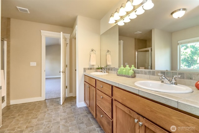 bathroom with double vanity, a shower stall, visible vents, and a sink