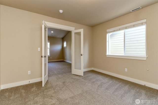 unfurnished room with french doors, carpet, visible vents, and a healthy amount of sunlight