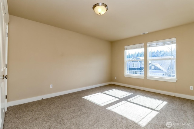 empty room featuring carpet floors, visible vents, and baseboards