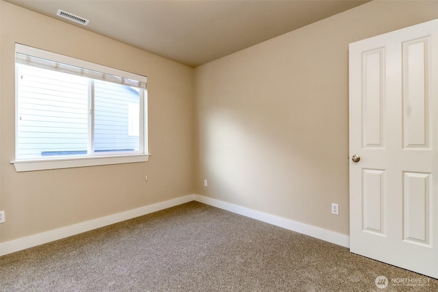 spare room with carpet floors, visible vents, and baseboards