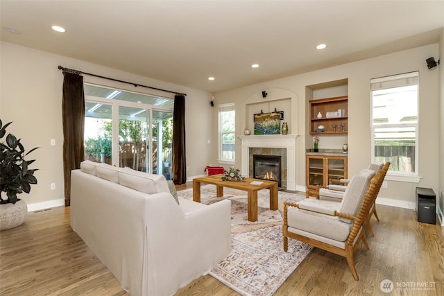 living area featuring light wood-style floors, baseboards, a tiled fireplace, and recessed lighting