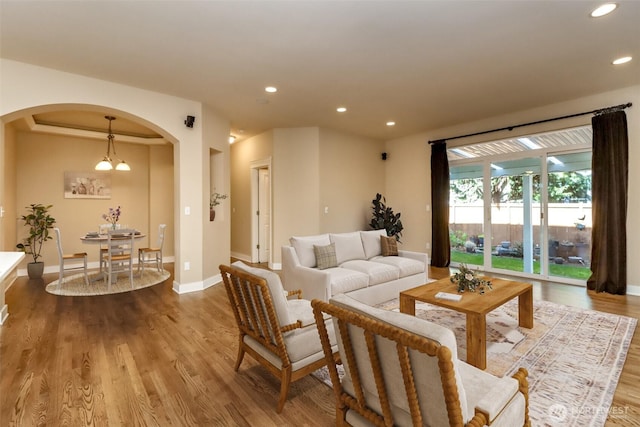 living room with recessed lighting, arched walkways, baseboards, and wood finished floors