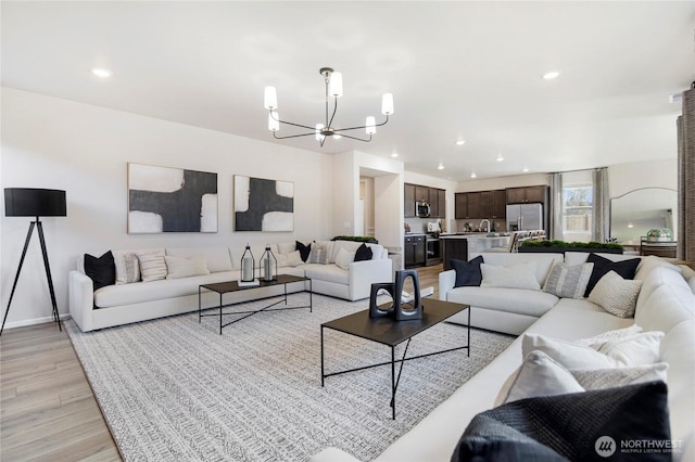 living room with sink, light wood-type flooring, and a chandelier