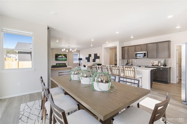 dining area with light hardwood / wood-style flooring and a chandelier