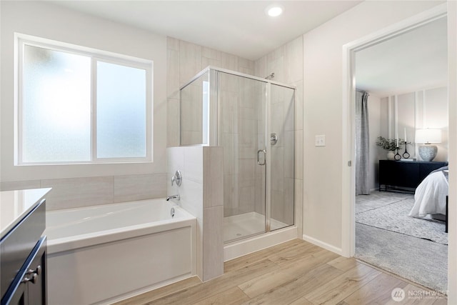 bathroom with hardwood / wood-style floors, plus walk in shower, and vanity