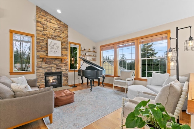 living area featuring high vaulted ceiling, light wood finished floors, and a fireplace