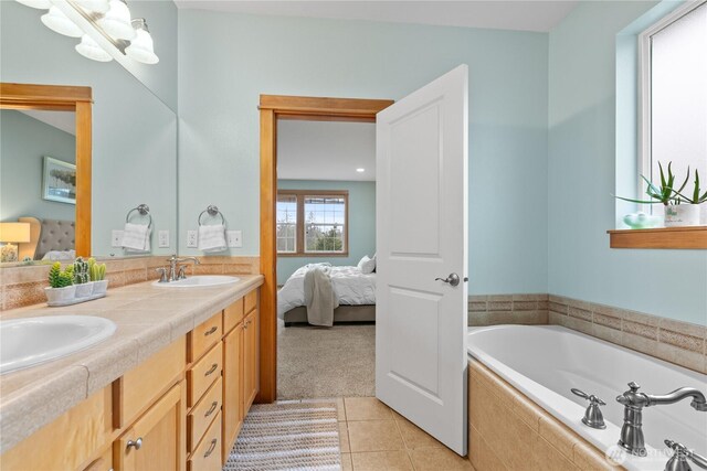 full bath with ensuite bathroom, a garden tub, a sink, tile patterned floors, and double vanity