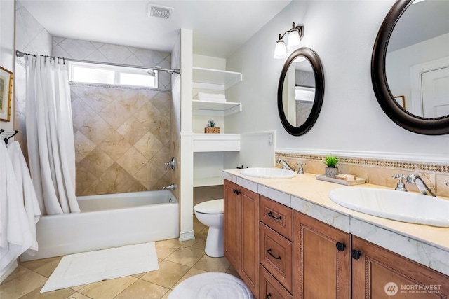 full bathroom featuring toilet, shower / bath combination with curtain, a sink, and visible vents