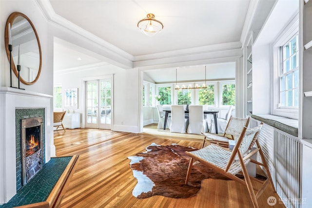 living room with french doors, ornamental molding, wood finished floors, a lit fireplace, and baseboards