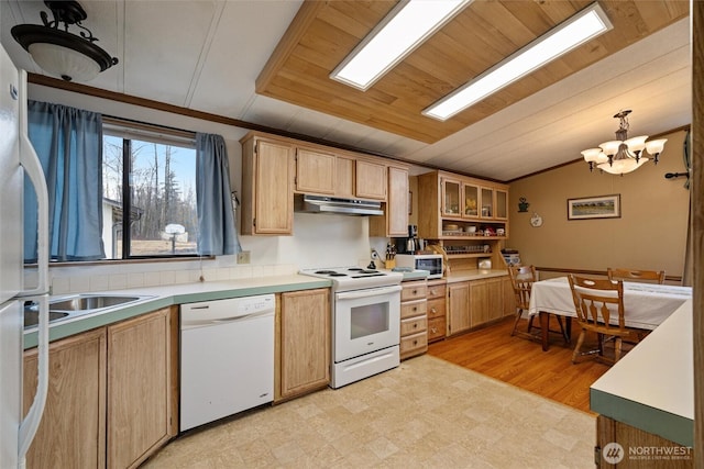 kitchen with under cabinet range hood, white appliances, light countertops, hanging light fixtures, and glass insert cabinets