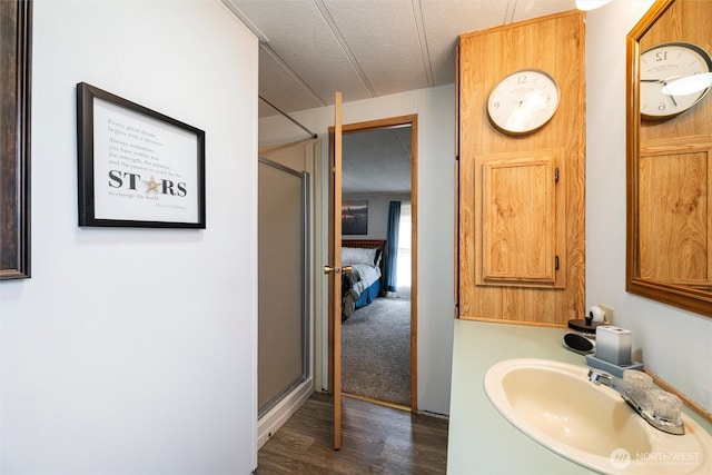 ensuite bathroom with wood finished floors, a stall shower, a sink, and connected bathroom