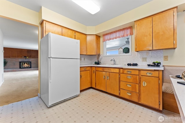 kitchen with light countertops, light floors, a sink, and freestanding refrigerator