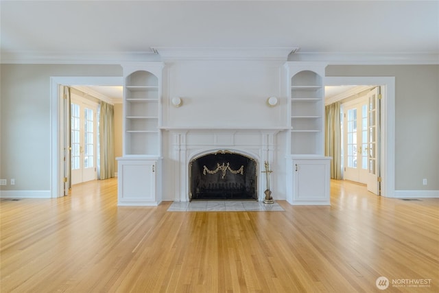 unfurnished living room with light wood-style flooring, a high end fireplace, and a wealth of natural light