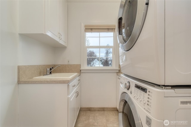 laundry area featuring stacked washer / drying machine, cabinet space, a sink, and light tile patterned floors