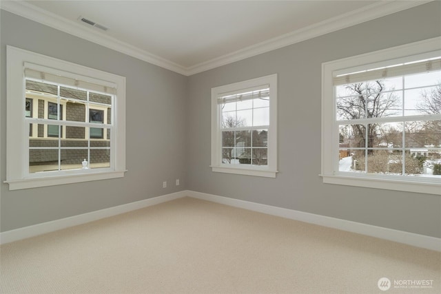 empty room with baseboards, visible vents, crown molding, and carpet flooring