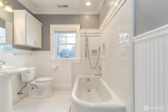 bathroom featuring a wainscoted wall, crown molding, bathing tub / shower combination, visible vents, and toilet