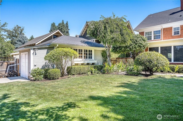 view of front of house featuring a garage, a front lawn, and fence