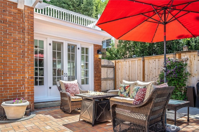 view of patio / terrace with an outdoor living space with a fire pit, french doors, and fence