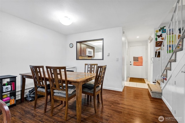 dining room featuring a baseboard heating unit and dark hardwood / wood-style flooring