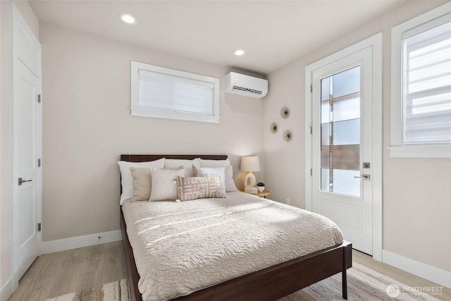 bedroom featuring a wall mounted AC and light hardwood / wood-style flooring