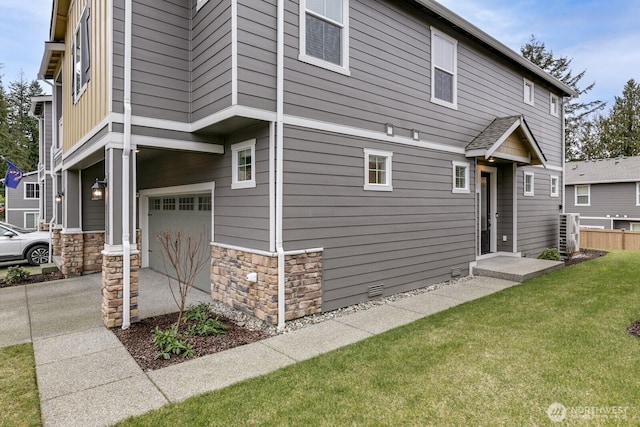 view of side of home featuring an attached garage, central air condition unit, a yard, stone siding, and crawl space