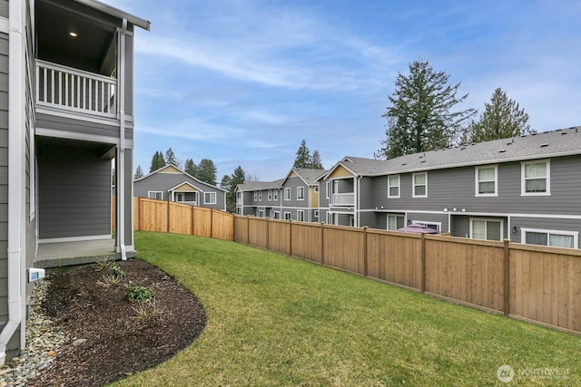 view of yard featuring a balcony, fence, and a residential view