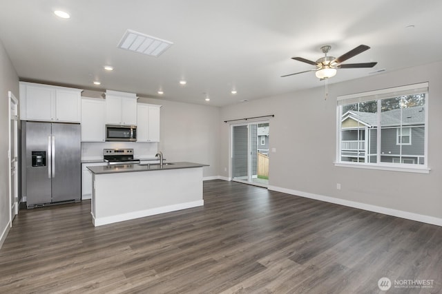 kitchen with dark wood finished floors, stainless steel appliances, a barn door, white cabinetry, and a sink