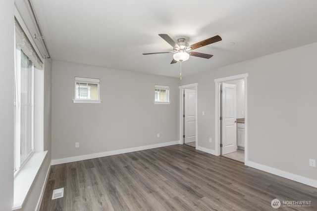 unfurnished bedroom featuring visible vents, ensuite bathroom, ceiling fan, wood finished floors, and baseboards