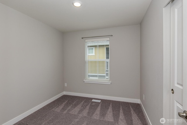 spare room with visible vents, baseboards, and dark colored carpet