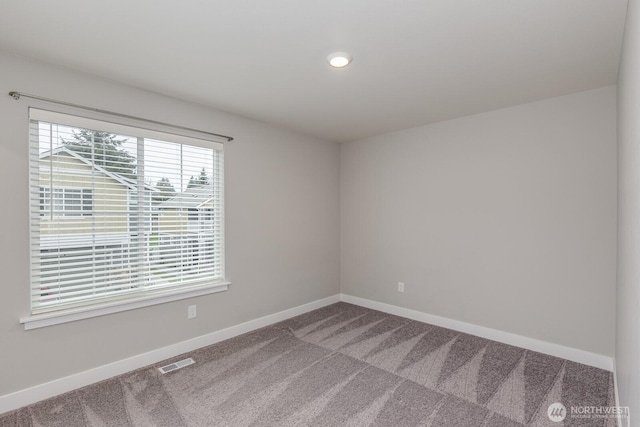 spare room with carpet, visible vents, and baseboards