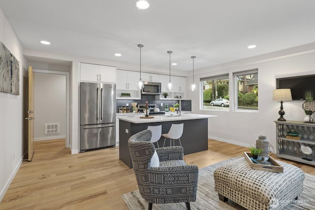 kitchen with visible vents, light wood-style floors, white cabinets, light countertops, and appliances with stainless steel finishes