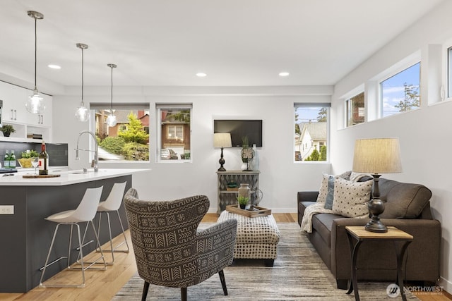 living room featuring recessed lighting, baseboards, and light wood finished floors