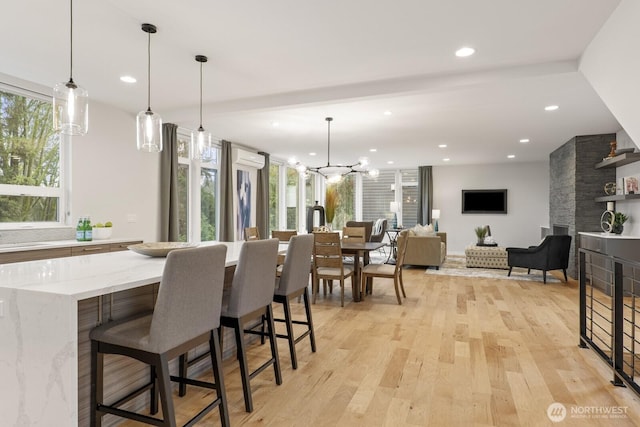 interior space with light wood finished floors, a large fireplace, an inviting chandelier, and recessed lighting