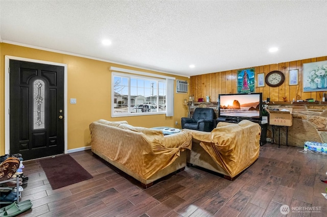 living room featuring crown molding, an AC wall unit, a textured ceiling, wood finished floors, and baseboards