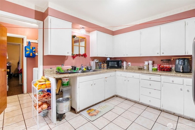 kitchen featuring light tile patterned floors, light countertops, white cabinetry, a sink, and black microwave