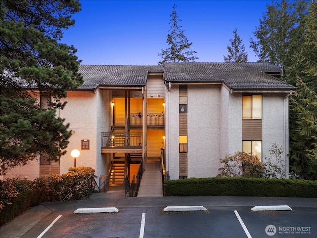 exterior space featuring stairs, uncovered parking, and stucco siding