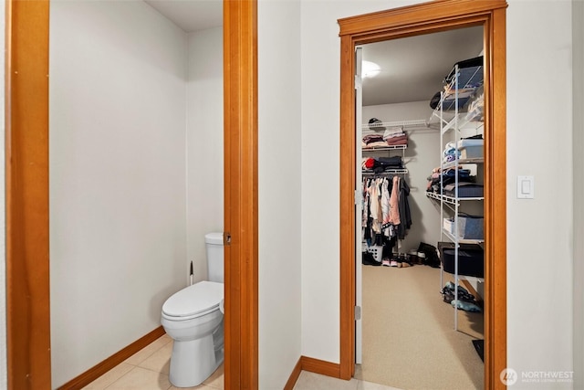 bathroom featuring baseboards, toilet, a spacious closet, and tile patterned flooring