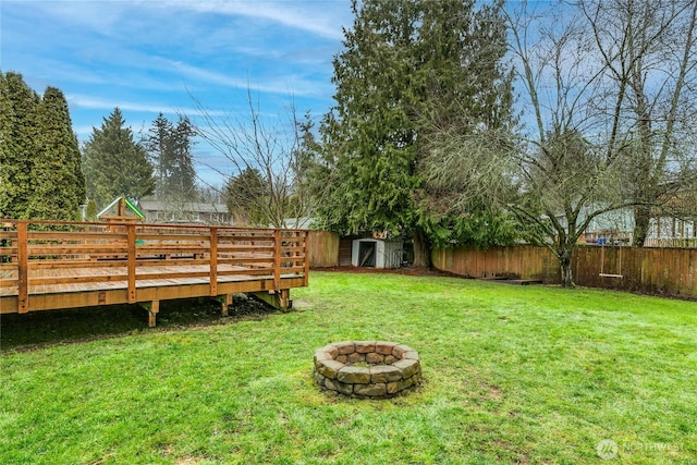 view of yard with a shed, a fire pit, and a wooden deck